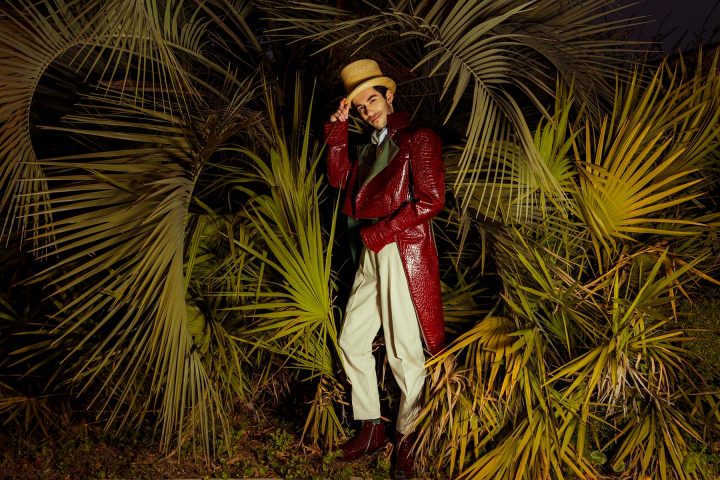 Circus ringmaster standing in front of palm fronds.