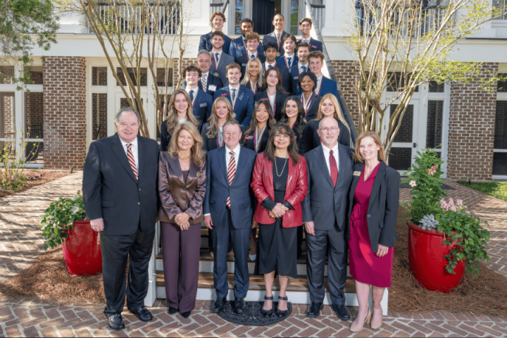 Group of people dressed in business attire standing on the stairs at the FSU President's house.
