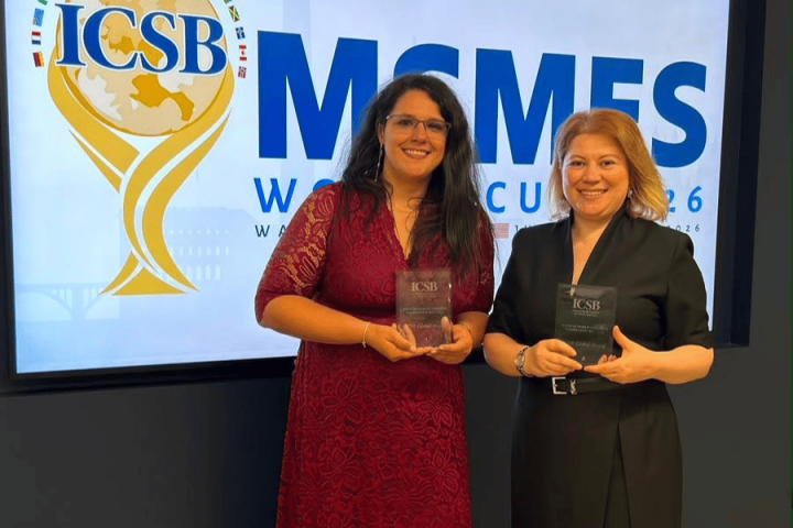 Two women are pictured holding transparent award plaques in front of a digital display backdrop.